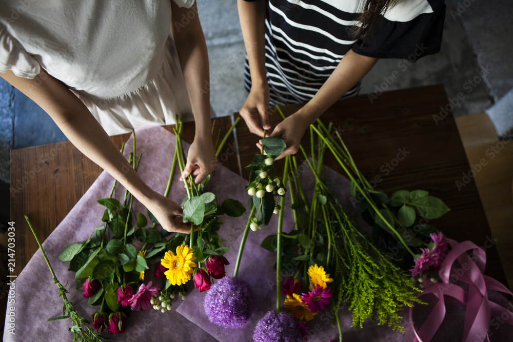 二人の女性が丁寧に花を選び、ひとつの花束を作り上げていく。