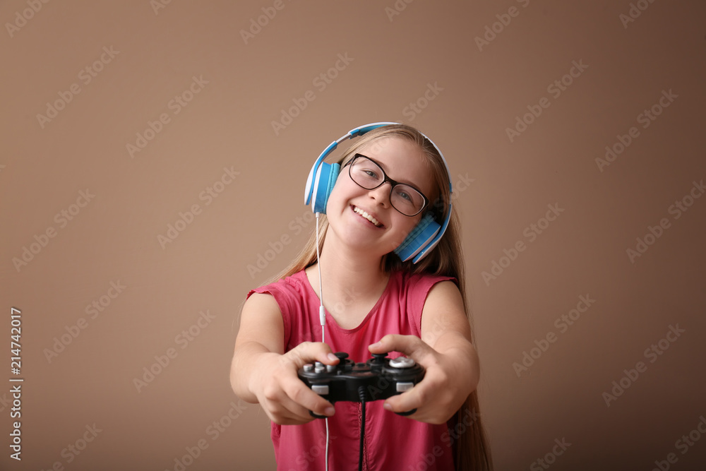 Cute girl with gamepad on color background