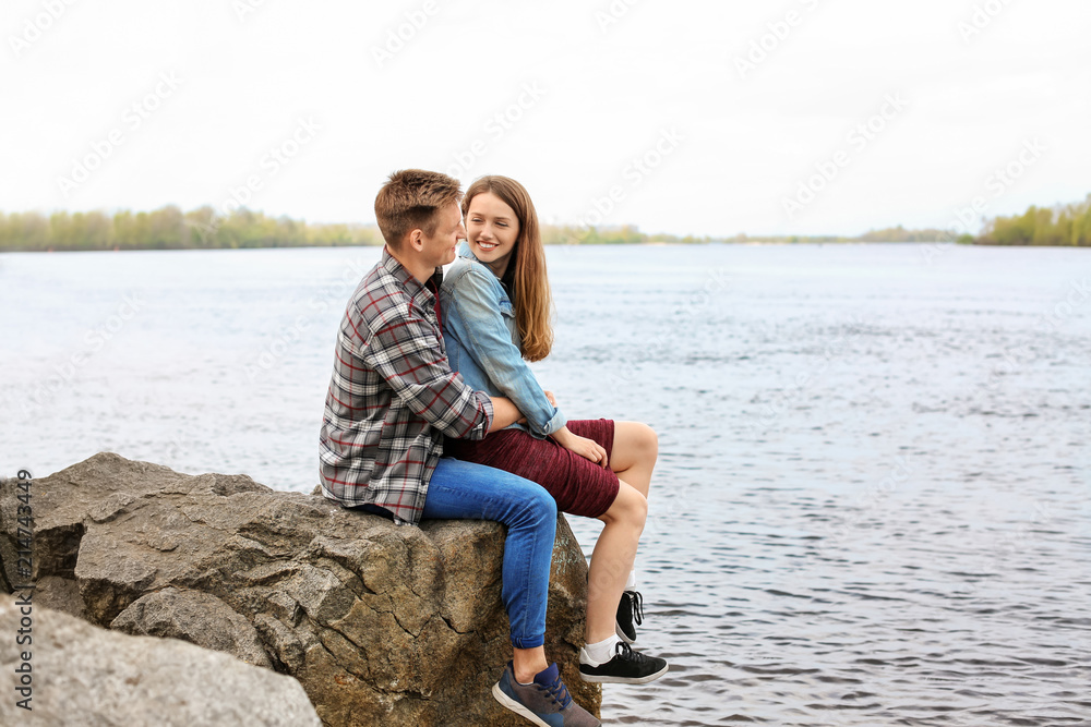 春日坐在河边的幸福的年轻夫妇