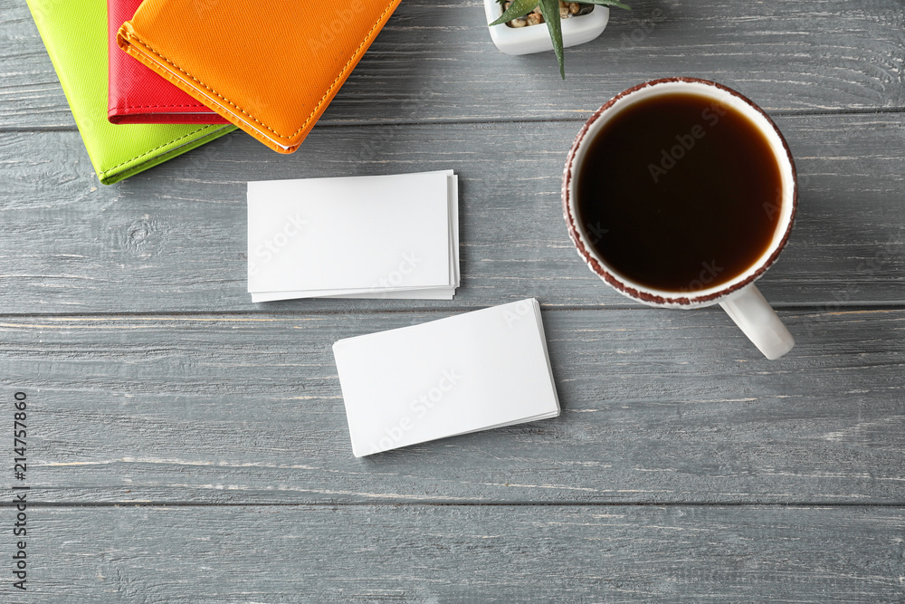 Blank business cards with notebooks and cup of coffee on wooden table