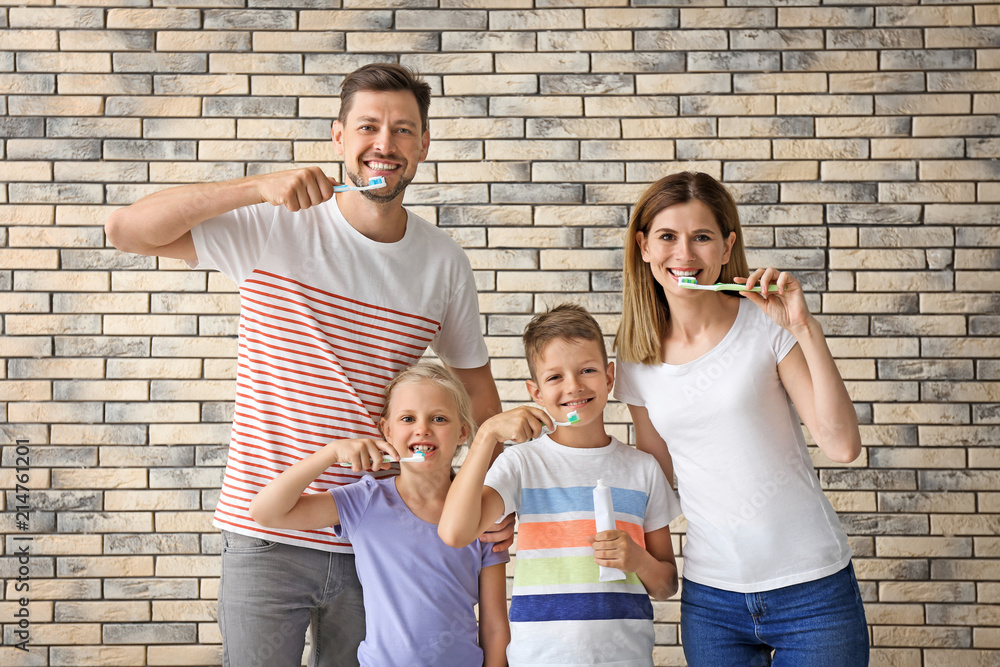 Family brushing teeth against brick wall