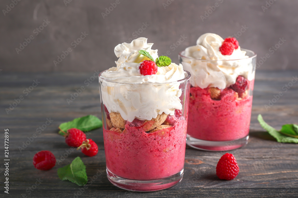 Glasses with tasty raspberry dessert on wooden table