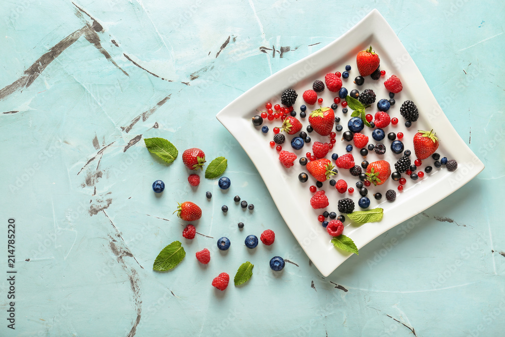 Plate with delicious ripe berries on light background, top view