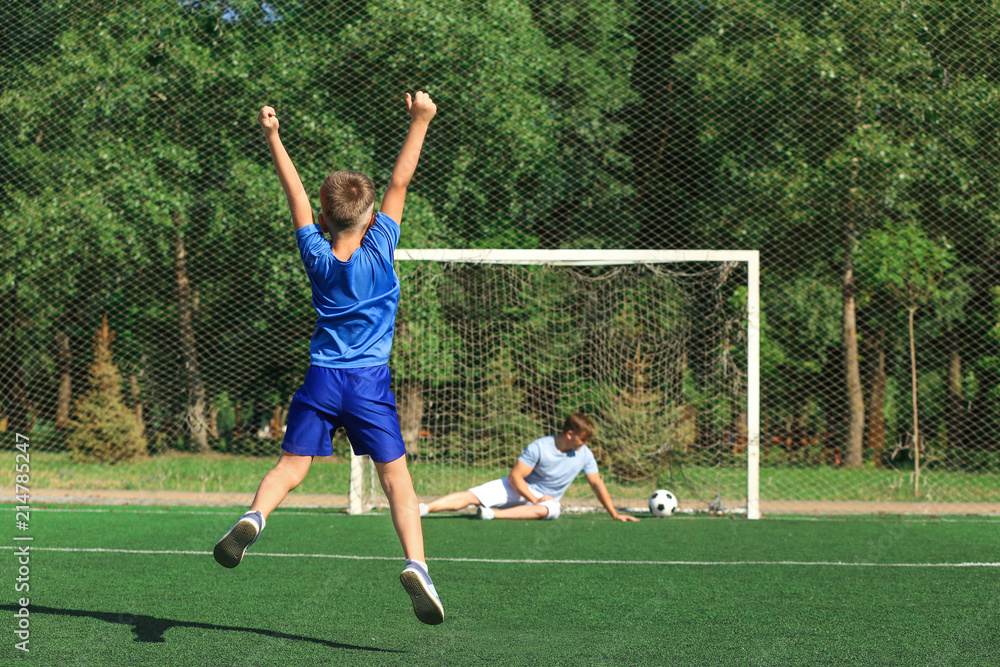 Happy boy with his dad playing football on soccer pitch