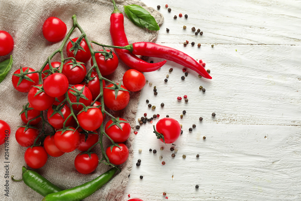 Fresh ripe cherry tomatoes and chili pepper on white wooden background