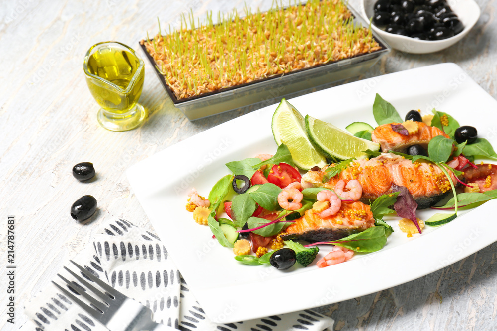 Plate with tasty fish and fresh salad on table