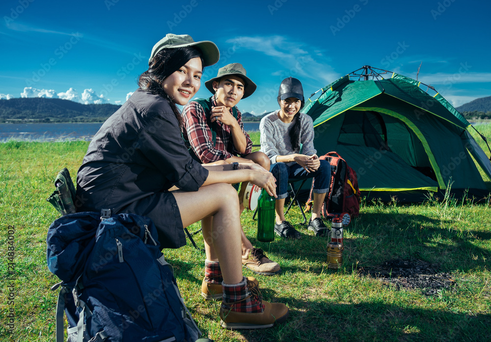 A  group of Asian friends sitting on chairs, singing, playing a guitar and drinking some beer and wa