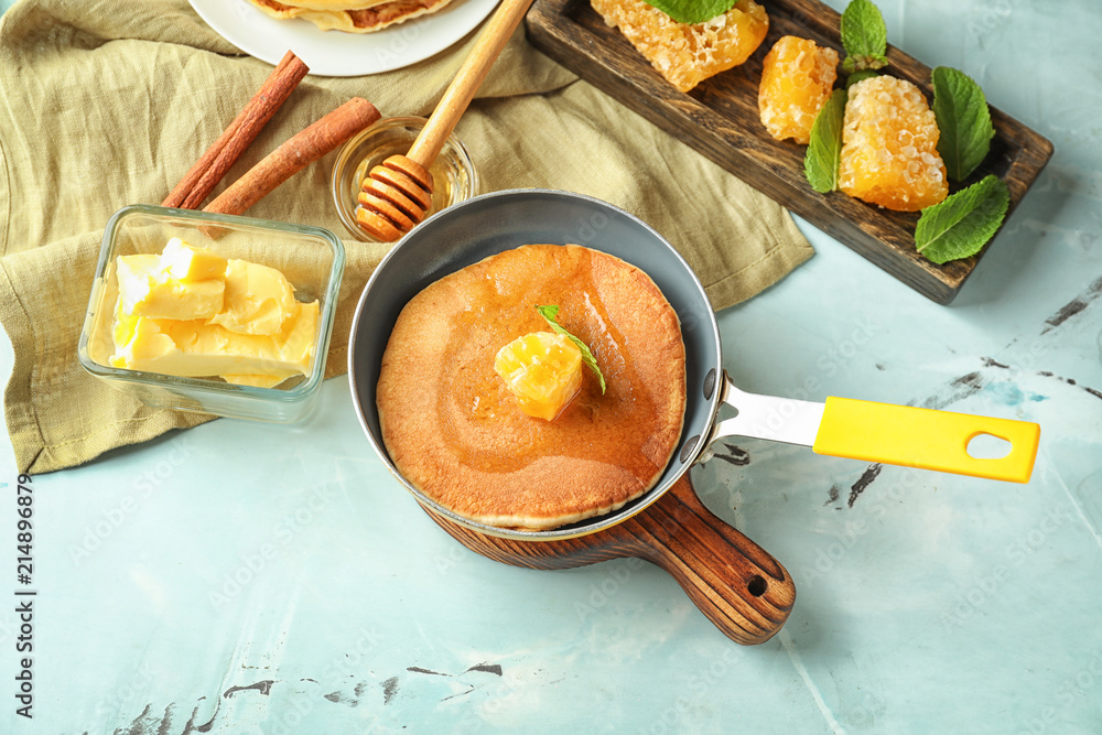 Frying pan with tasty pancake and honeycomb on table