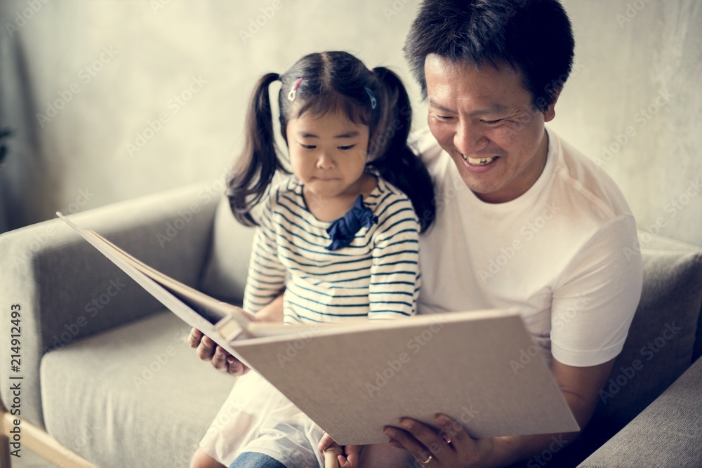 Asian father and daughter reading together