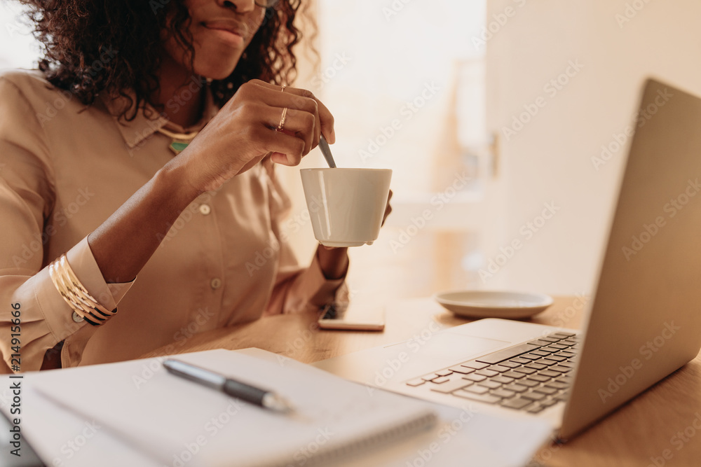 女人在家用笔记本电脑工作时拿着一杯咖啡