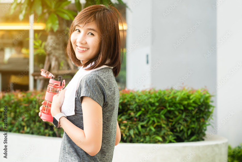 亚洲女性下午运动后拿着一瓶水休息