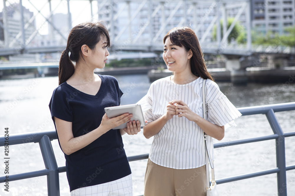 橋の近くでタブレットを持ちながら立ち話をしている女性たち