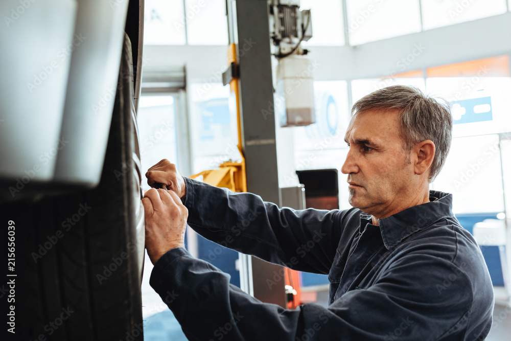 Mechanic replacing wheel of a car in garage