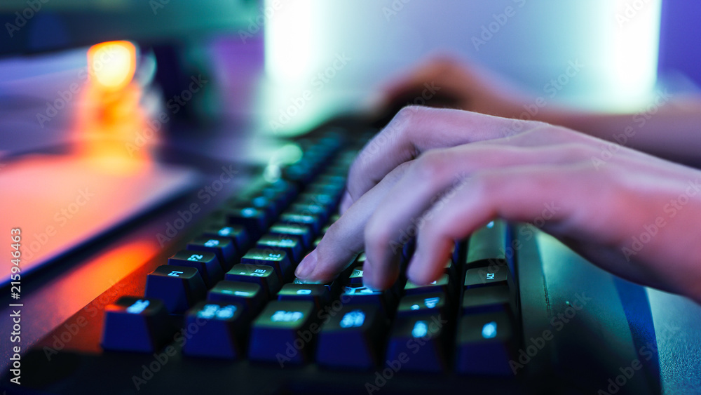 Close-up on the Hands of the Gamer Playing in the Video Game on a Keyboard. Stylish Arcade Neon Brig