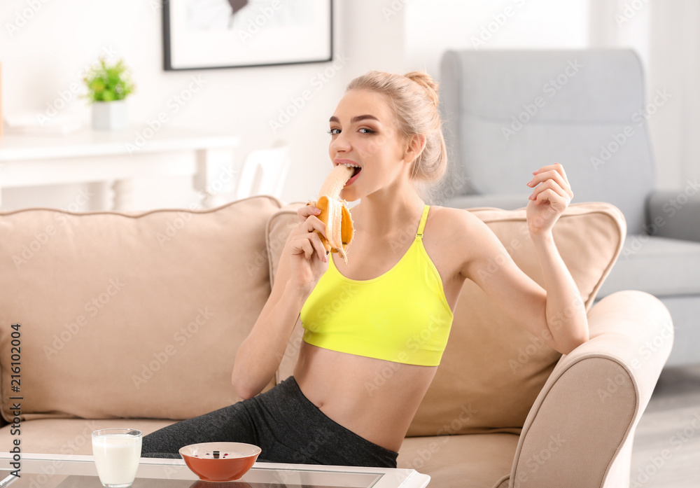 Young woman eating banana at home. Diet food concept