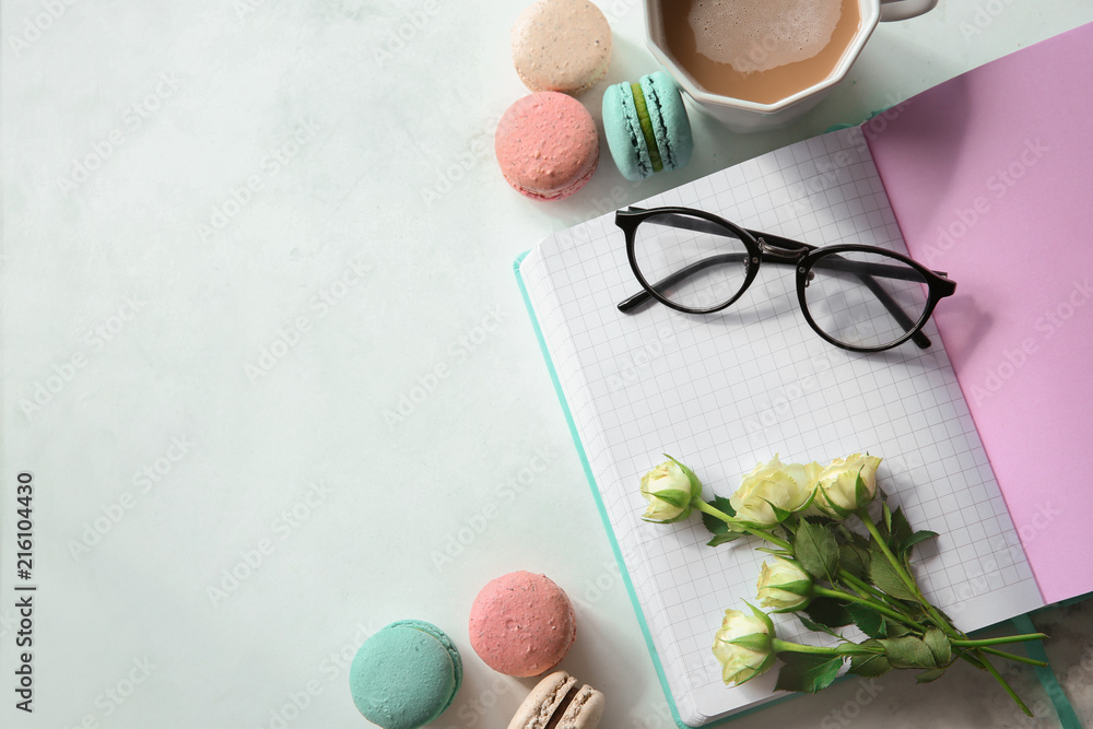 Flat lay composition with tasty macarons, notebook and cup of coffee on light background