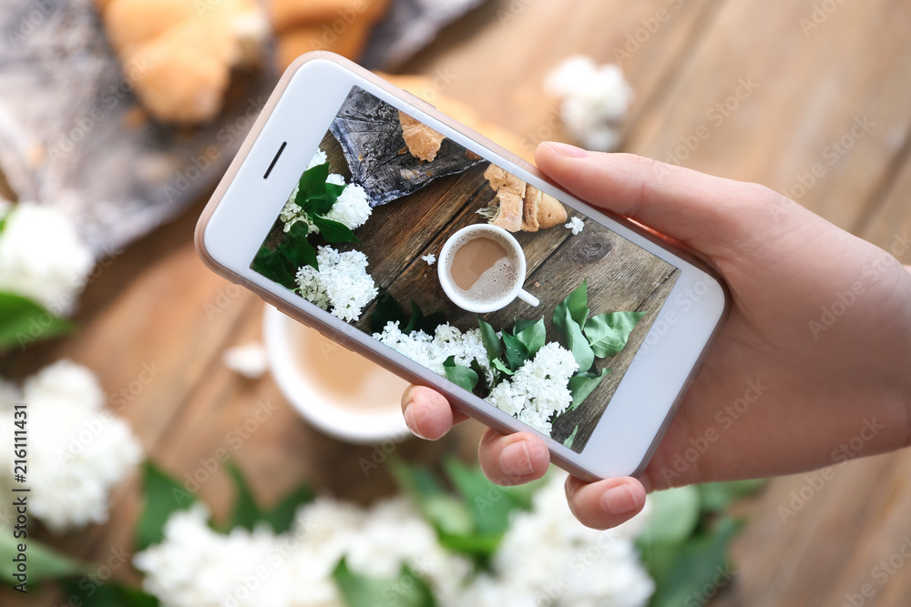 Woman taking photo of blossoming lilac and cup with coffee, closeup