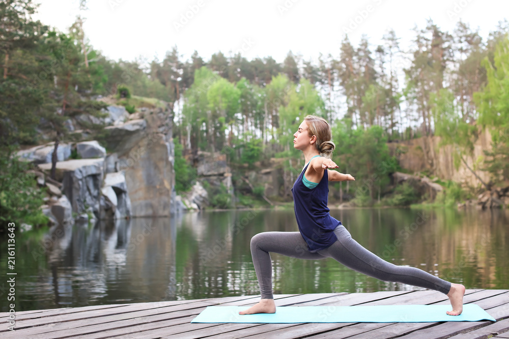 Beautiful young woman practicing yoga outdoors in morning