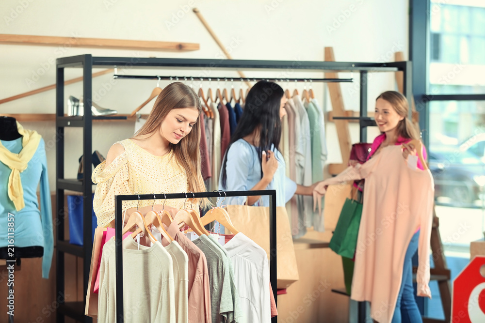 漂亮的年轻女孩在店里挑选衣服