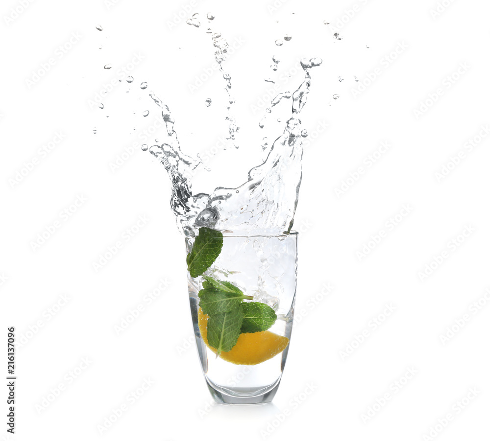 Glass with splashing water and sliced citrus fruit on white background