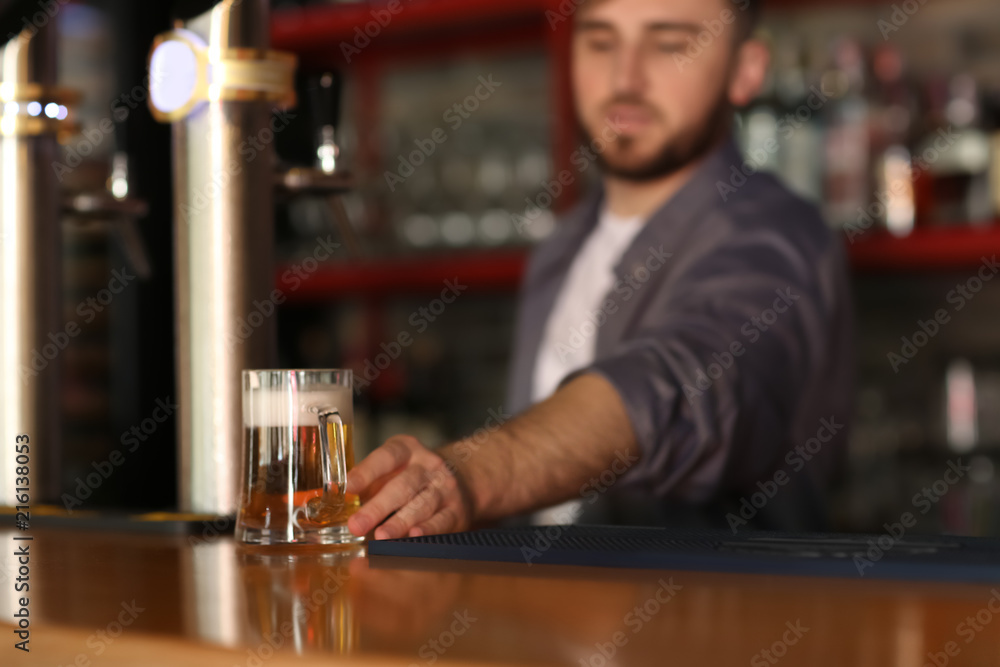 酒吧里拿着一杯啤酒的调酒师