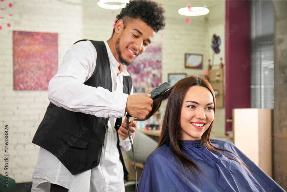 Professional hairdresser working with client in beauty salon