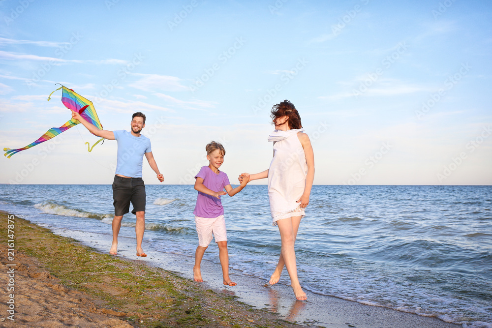 Happy family flying kite near sea