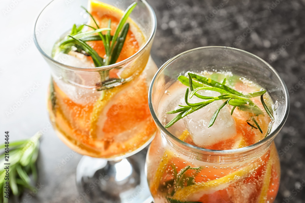 Glasses with fresh cold grapefruit cocktail and rosemary on table