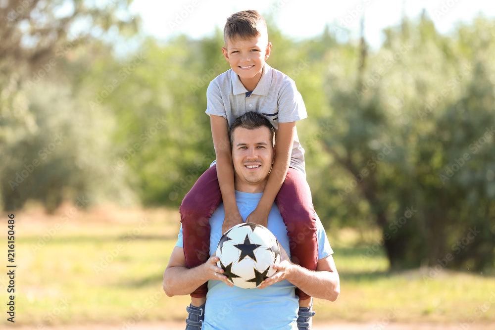 Little boy and his dad with soccer ball outdoors