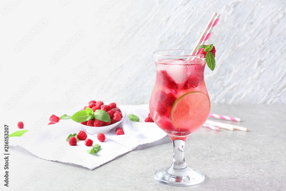 Glass of fresh raspberry mojito on table