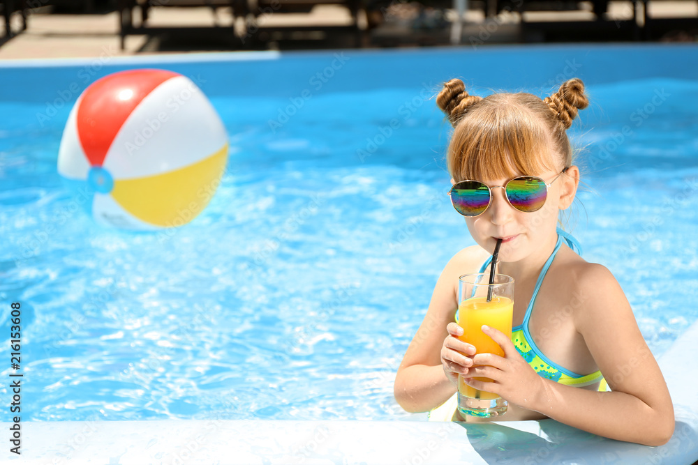 Cute little girl drinking juice in swimming pool