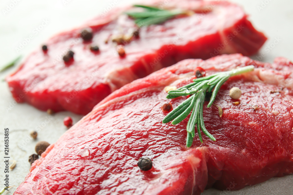 Raw meat with spices and rosemary on grey background, closeup