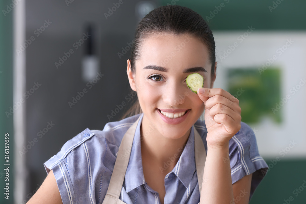 厨房里拿黄瓜片的有趣年轻女人