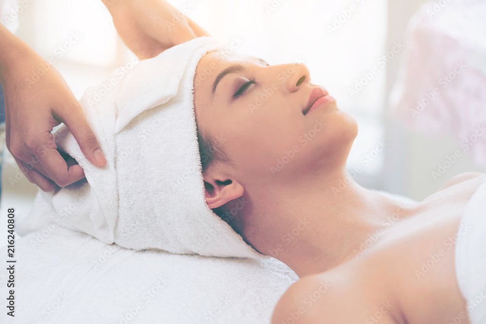 Relaxed young woman lying on spa bed for massage.