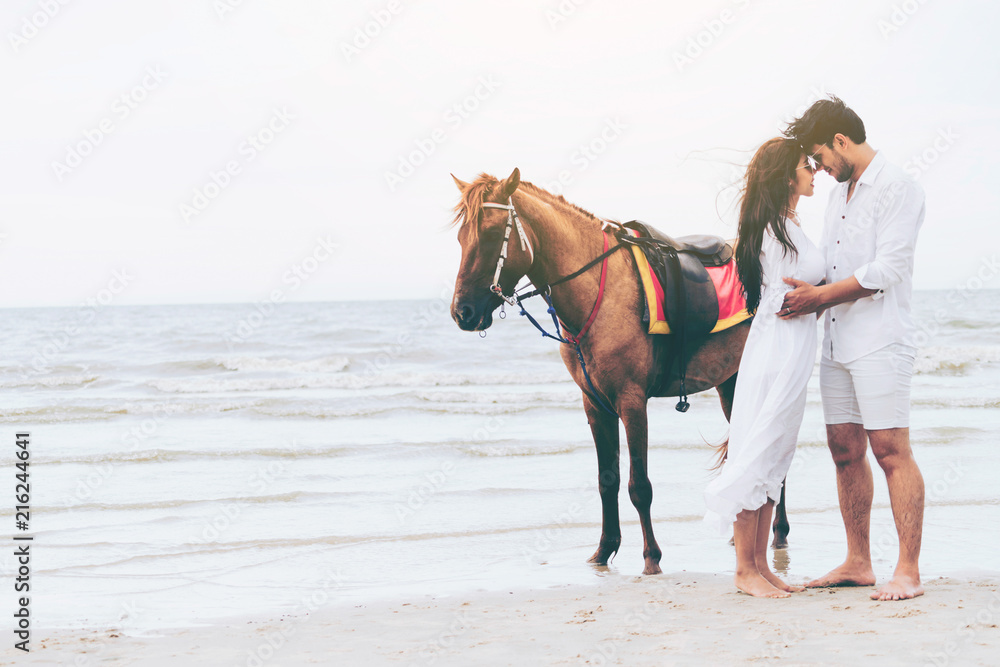 Young couple goes horse riding on tropical beach.