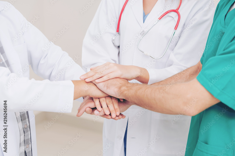 Doctor, surgeon and nurse join hands together.