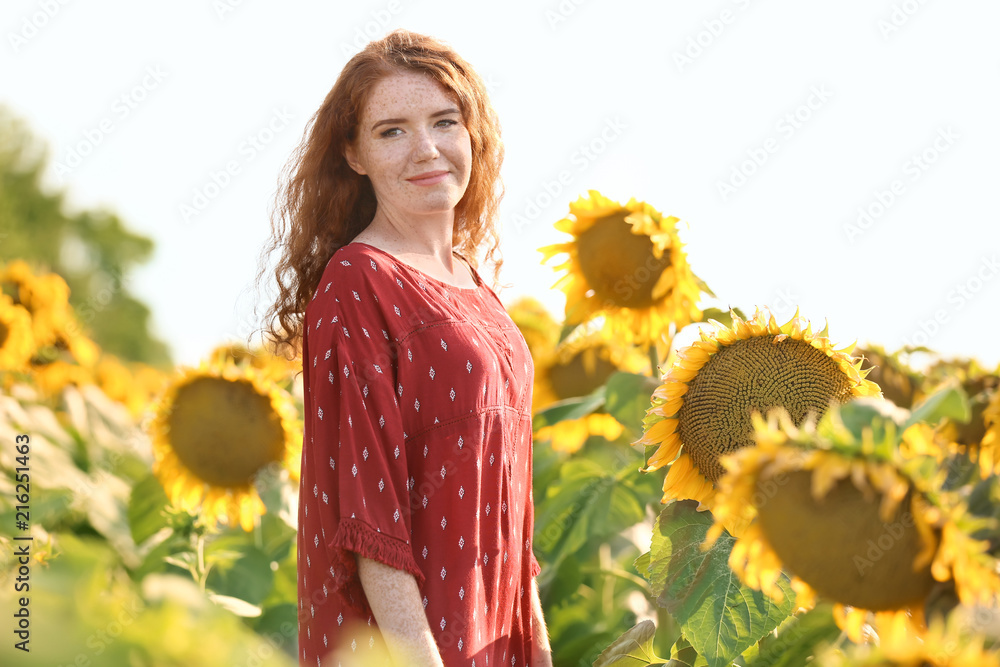 阳光明媚的向日葵地里美丽的红发女人