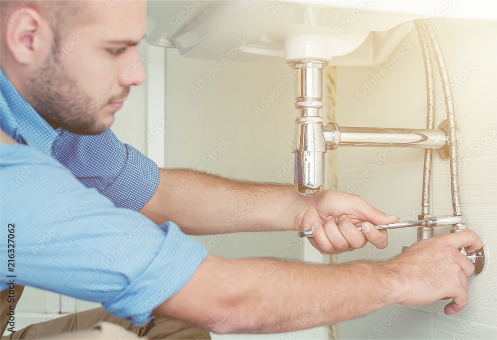 Handsome Professional plumber fixing pipes