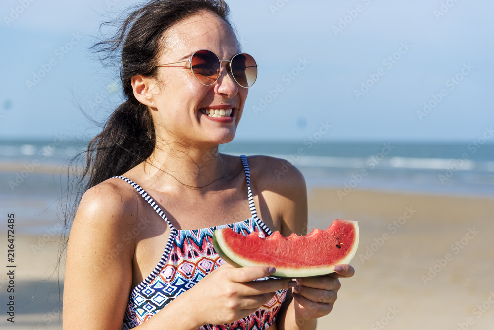 海滩上拿着西瓜的年轻女子