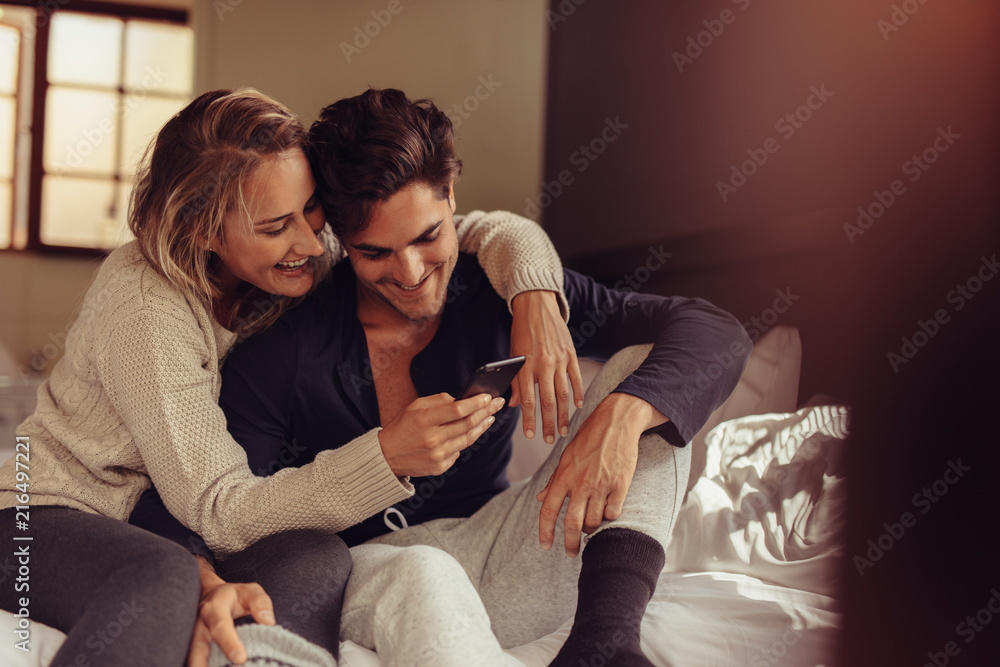 Relaxed couple looking at mobile phone