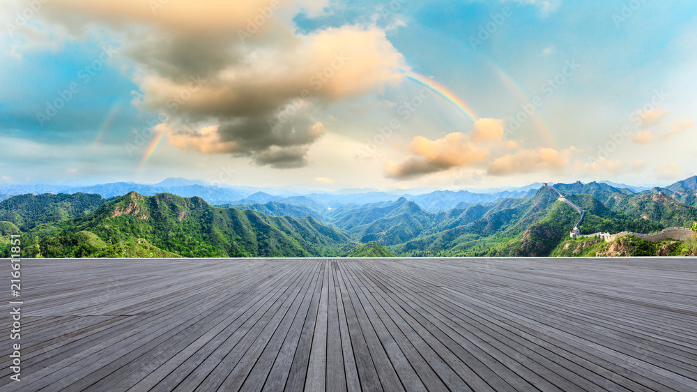 Wood square floor and mountains with rainbow at sunset