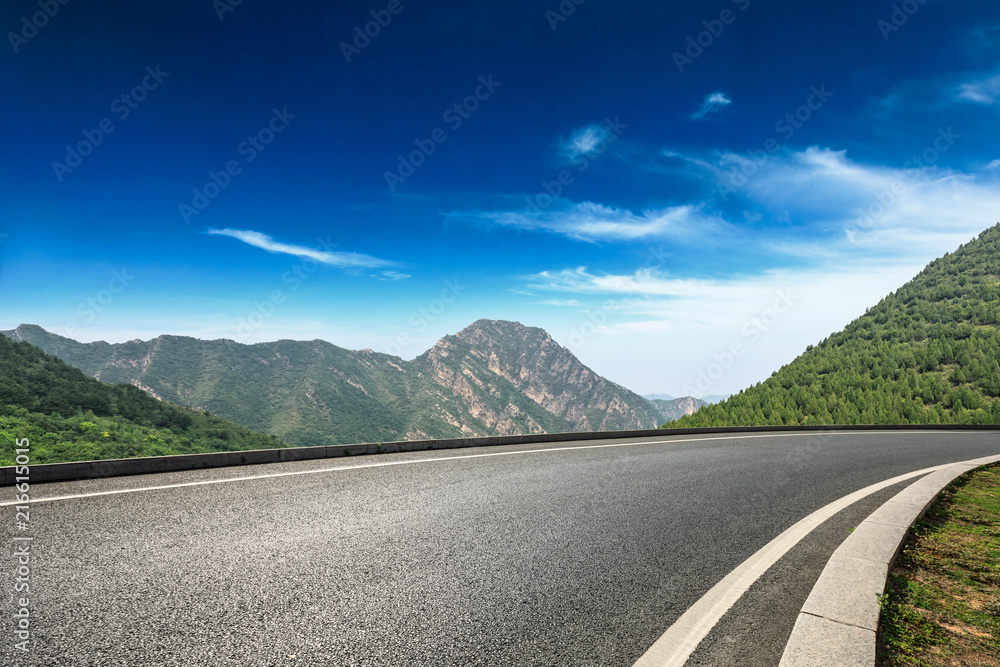 空旷的柏油路和蓝天下的群山自然风光