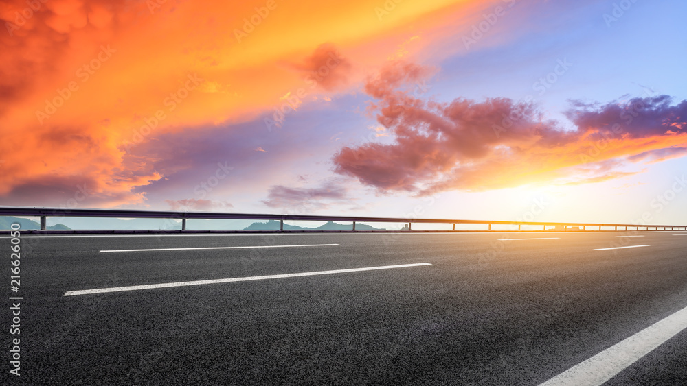 Empty asphalt road and great wall with mountains at sunset