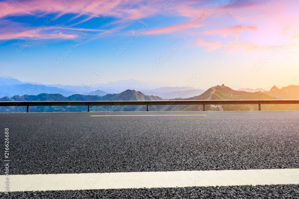 Empty asphalt road and great wall with mountains at sunset