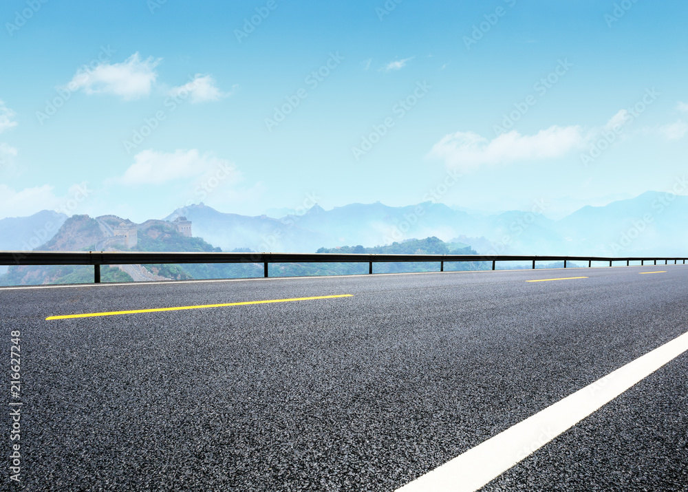 Empty asphalt road and great wall with mountains at dusk