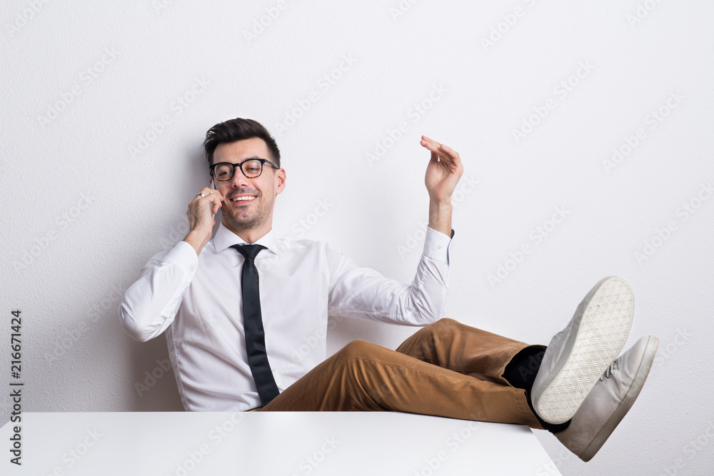 Portrait of a young man with smartphone in a studio, making a phone call.