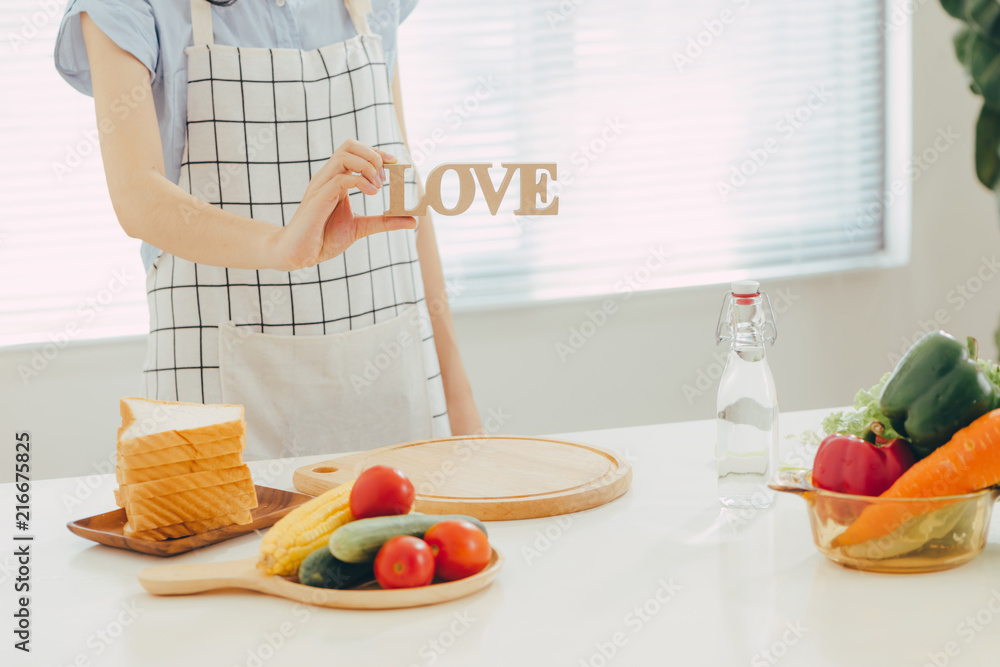 一个女人拿着木制字母LOVE在厨房做饭。