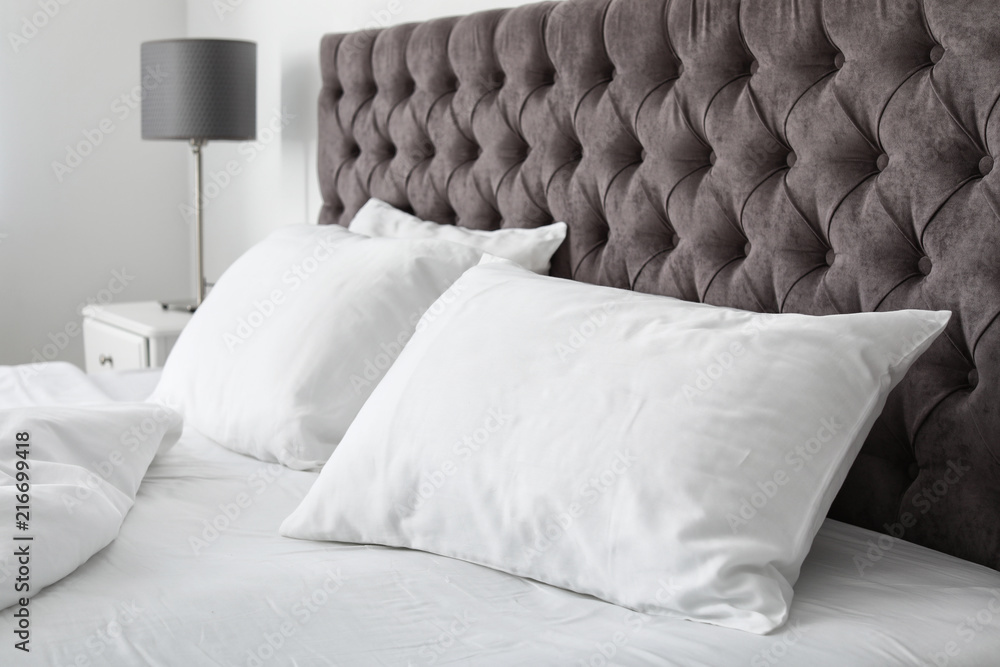 Soft white pillows on comfortable bed indoors