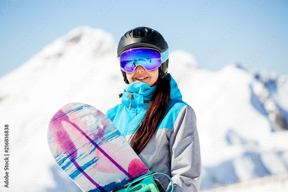 雪山背景下带滑雪板的年轻女游客头盔照片