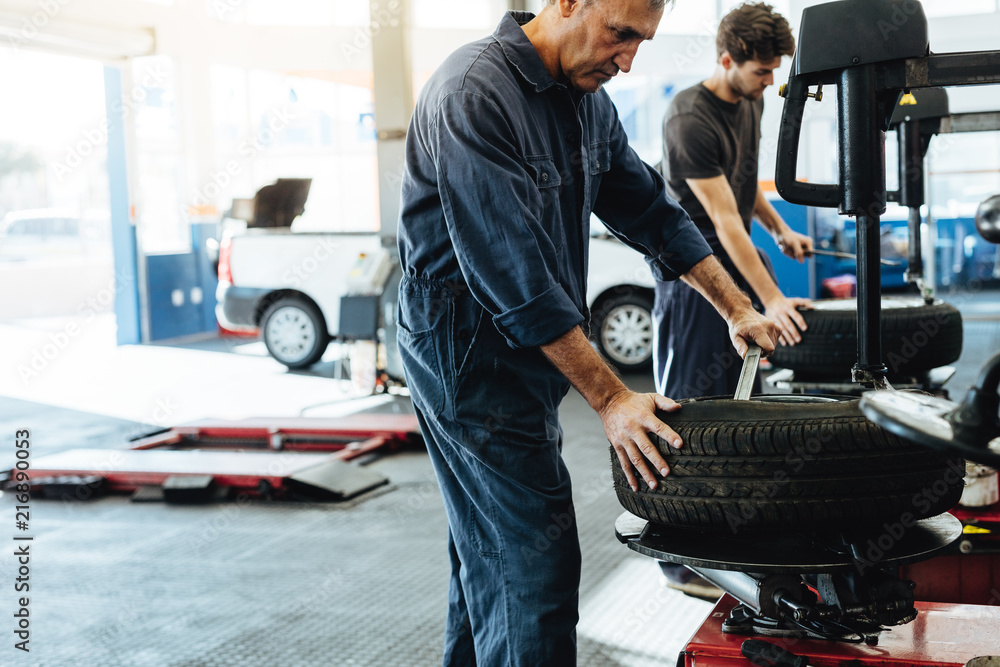 Mechanics working on tire replacing machines in service station